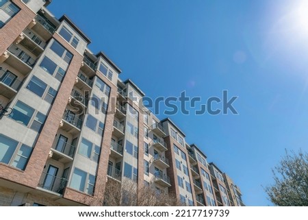 Austin, texas- Mid-rise apartment complex in a low angle view. Facade of an apartment building with picture windows and balconies with bicycles on some railings.