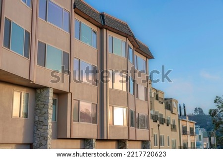 Apartment building with reflective glass windows in San Francisco,CA. Row of apartment buildings starting at the building at the front with stones at the pillars beside the apartment with balconies.