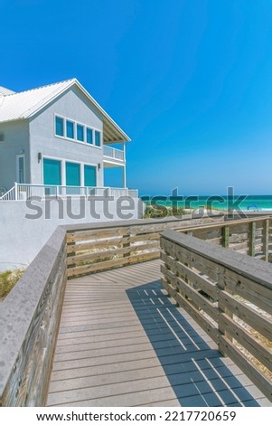 Destin, Florida- Boardwalk with a view of beach house and ocean. Wooden walkway outside a beach house against the view of the blue ocean and sky.