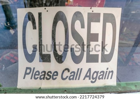 San Antonio, California- Signage with Closed Please Call Again. Selective focus of signage behind glass wall with reflection outdoors.