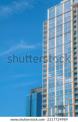 Residential building exterior seen at a housing area in downtown Austin Texas. City skyline with apartments or businesses against a cloudless blue sky background.