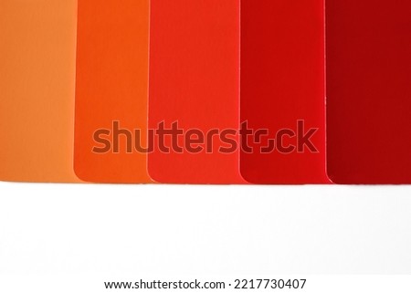 Evenly spaced color swatches coming from the top of the frame, with copy space underneath. Swatches are in shades of orange to red. Autumnal colors. Fall color schemes. Design inspiration and concepts