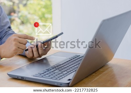 Online communication business technology concept. Email, send, receive, inbox, Hand of businessman using mobile smartphone in home office with notification 1 new email alert sign icon pop up.