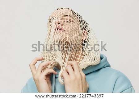 a close horizontal photo of a sad, tired man with a mesh on his face, holding his hands on his head