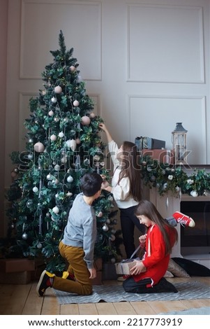 Three children a girl and a boy in festive attire are in a room decorated for the New year and Christmas. The concept of holidays and gifts.