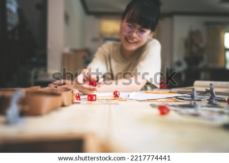 Role playing tabletop and board games hobby concept. Focus on dice d20. Blur background with hand and monster miniatures. Royalty-Free Stock Photo #2217774441