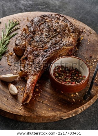 Barbecue Tomahawk Steak on Cutting Board. Steak on the bone. Succulent grilled tomahawk beef steak close up. Royalty-Free Stock Photo #2217783451