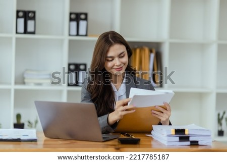 Happy smiling business woman Working on laptop computer with paperwork at desk in a modern office,  business finance technology concept.