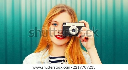 Close up portrait of teenager girl with film camera taking a picture in the city