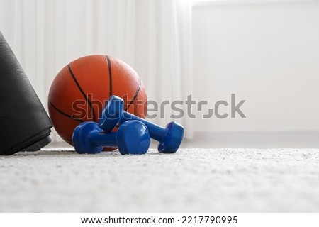 Dumbbells and ball on floor in light room