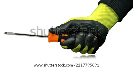 Manual worker with black and green protective work gloves holding a flat head screwdriver with black and orange plastic handle. Isolated on white background with reflections.