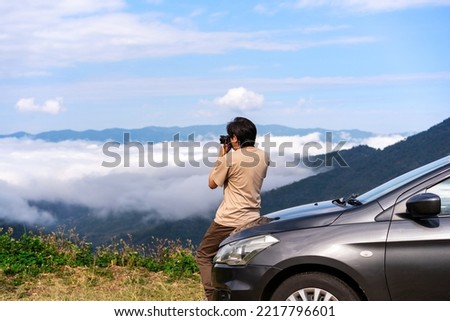 Young man travelers with a car taking photos at beautiful sea of fog over the mountain while travel driving road trip on vacation