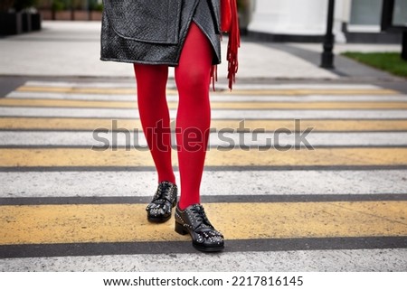 Woman legs in red color tights, black leather shoes with rivets and skirt stand on crosswalk. Fashion details for stylish extravagant women Royalty-Free Stock Photo #2217816145