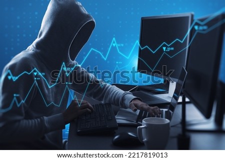 Side view of hacker using computers at desktop with abstract glowing blue business graph hologram on blurry background. Economy, finance, hacking, data theft and digital money concept