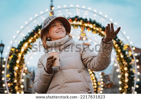 Girl cup hot drink while walking in Christmas market decorated with holiday lights in the evening. happy in big city. Spending winter vacations Moscow, Russia