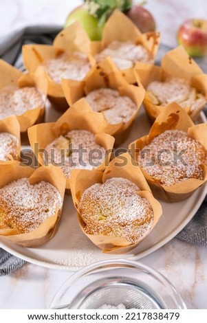 Garnishing freshly baked apple sharlotka muffin dusted with powdered sugar.