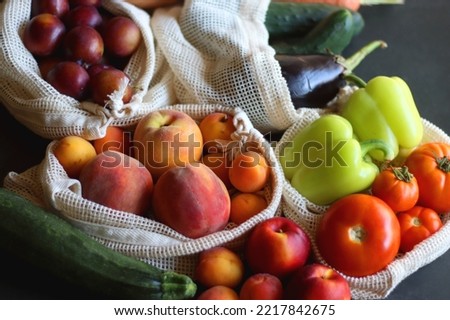 Reusable mesh bags for fruits and vegetables, filled with various healthy food. Dark background, selective focus.