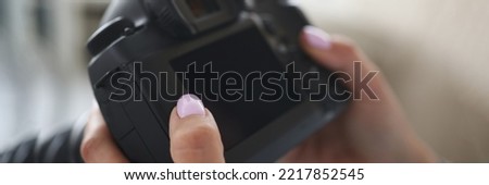 Woman go through pics in photocamera, choose good ones after photoshot
