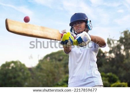 Female Indian cricket player wearing protective gear and hitting the ball with a bat on the field