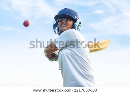 Female Indian cricket player wearing protective gear and hitting the ball with a bat on the field Royalty-Free Stock Photo #2217859683