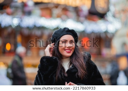 Beautiful dark-haired young woman in an eco fur coat walks around the city and does Christmas shopping. New Year holidays. Present. Holidays.