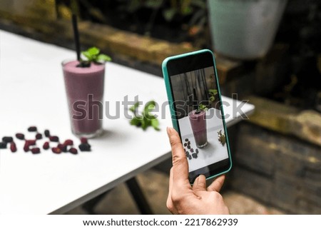 A woman taking picture of mulberry smoothie for advertisement and social media