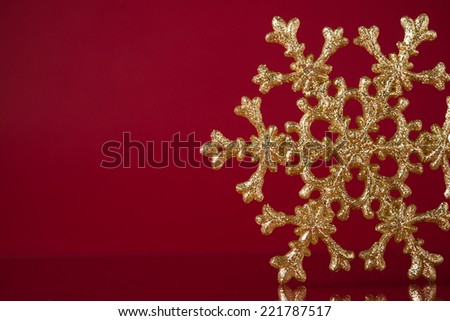 Christmas golden snowflake on dark red background with space for text. Xmas holiday theme.
