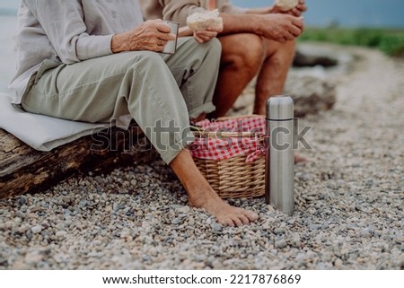 Low section of senior couple enjoying picnic outdoor near sea. Royalty-Free Stock Photo #2217876869
