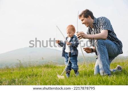 Father teaching son to use bow and arrow