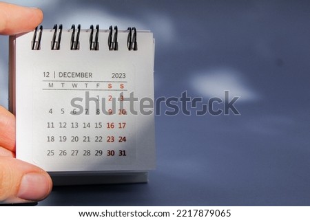 The hand holds a small calendar on which December 2023. High quality photo