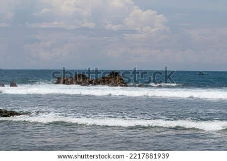 view, wallpaper of Wedi Ombo beach in Yogyakarta Indonesia with rows of rocks around the beach. view of the rock with moderate waves during the day