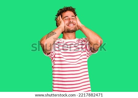 Young caucasian curly hair man isolated Young caucasian man with curly hair isolated laughs joyfully keeping hands on head. Happiness concept.