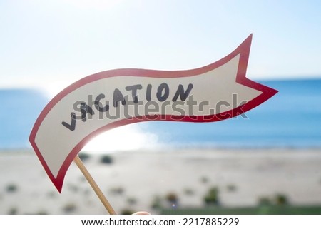 Stick with paper speech bubble with words Vacation on background sea, sky, sandy beach on a sunny summer day. Text-balloons with text from letters. Concept, symbol, sign vacation travel tourism rest.