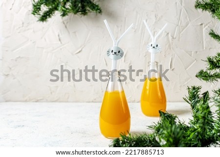 Orange drink decorated with white rabbit on light background for children party. Christmas funny food concept for kids