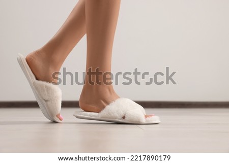 Woman wearing white soft slippers indoors, closeup. Space for text Royalty-Free Stock Photo #2217890179