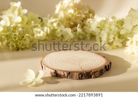 Wooden round podium with flowers and shadows on pastel background. Empty natural stand for presentation and exhibitions for organic cosmetic product. Mockup