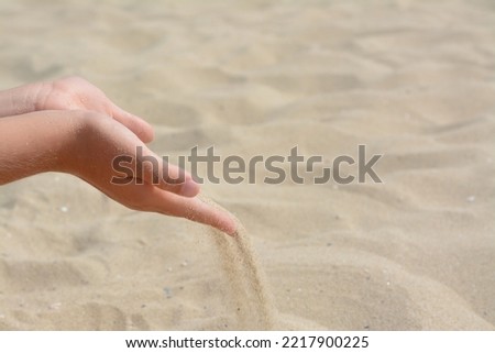 Child pouring sand from hands on beach, closeup with space for text. Fleeting time concept