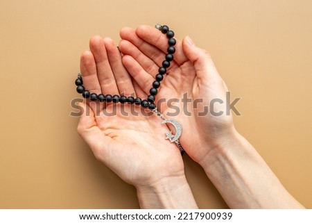 Islamic prayer concept. Hands holding Muslim rosary with silver crescent moon