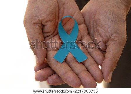 Hand holding a blue ribbon. Blue november