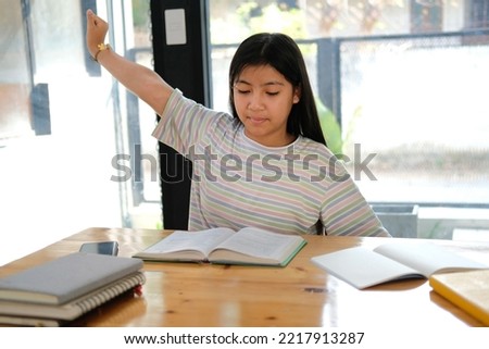 asian girl student stretching while reading book feeling tired bored sleepy. children education