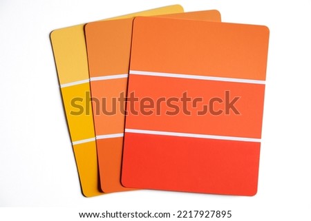 Generic sample color swatches laid out on a table. Swatches are in light to dark shades of autumnal yellows and oranges. Fall color schemes. Interior design color pallet.