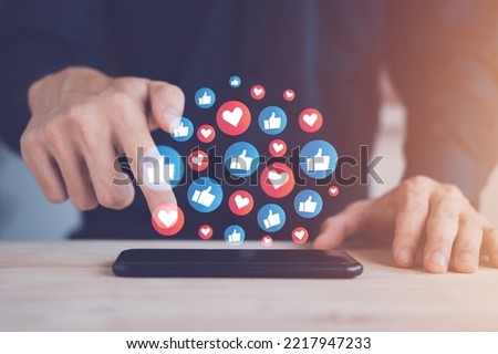 Chat and notification on smartphone with virtual red heart and blue like emoji social media icon. Man using smartphone on vacation with hologram. Social media and digital online concept.