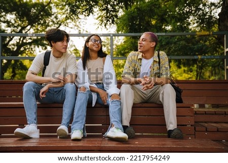 Three multiracial friends laughing and talking during spending time together in skate park
