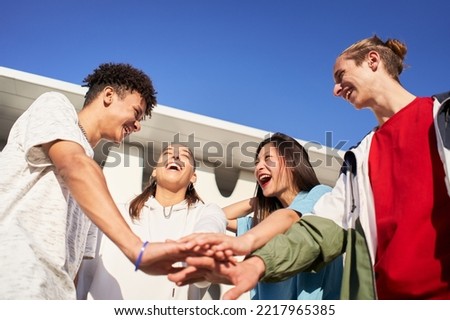 Happy young friends stacking hands. Diverse group of people celebrating and having fun together. High quality photo