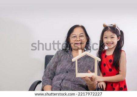 Concept housing family. Grandmother and child with house model.