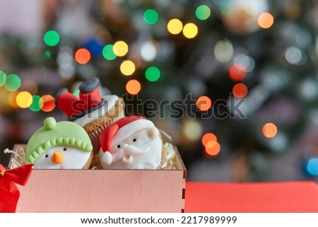 Festive holidays present - Christmas cupcakes in wooden box in front of the bokeh of Christmas tree. Good holidays mood. Selective focus