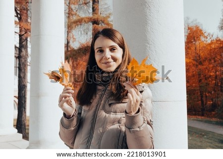happy smiling woman holding in her hands yellow maple leaves. Autumn mood concept. Girl having fun time outside in autumn park