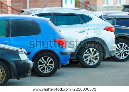 Close-up of the back of a frozen frosted blue car with other cars parked in a parking lot on a city street.Rest stoр. 