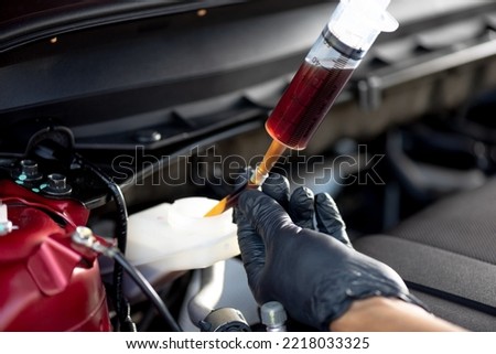 Technician changing brake fluid. Car maintenance concept. Royalty-Free Stock Photo #2218033325