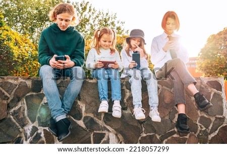 Teenager boy and a sister girls kids sitting and browsing their smartphone devices. Careless young teenhood time and a modern technology concept image.